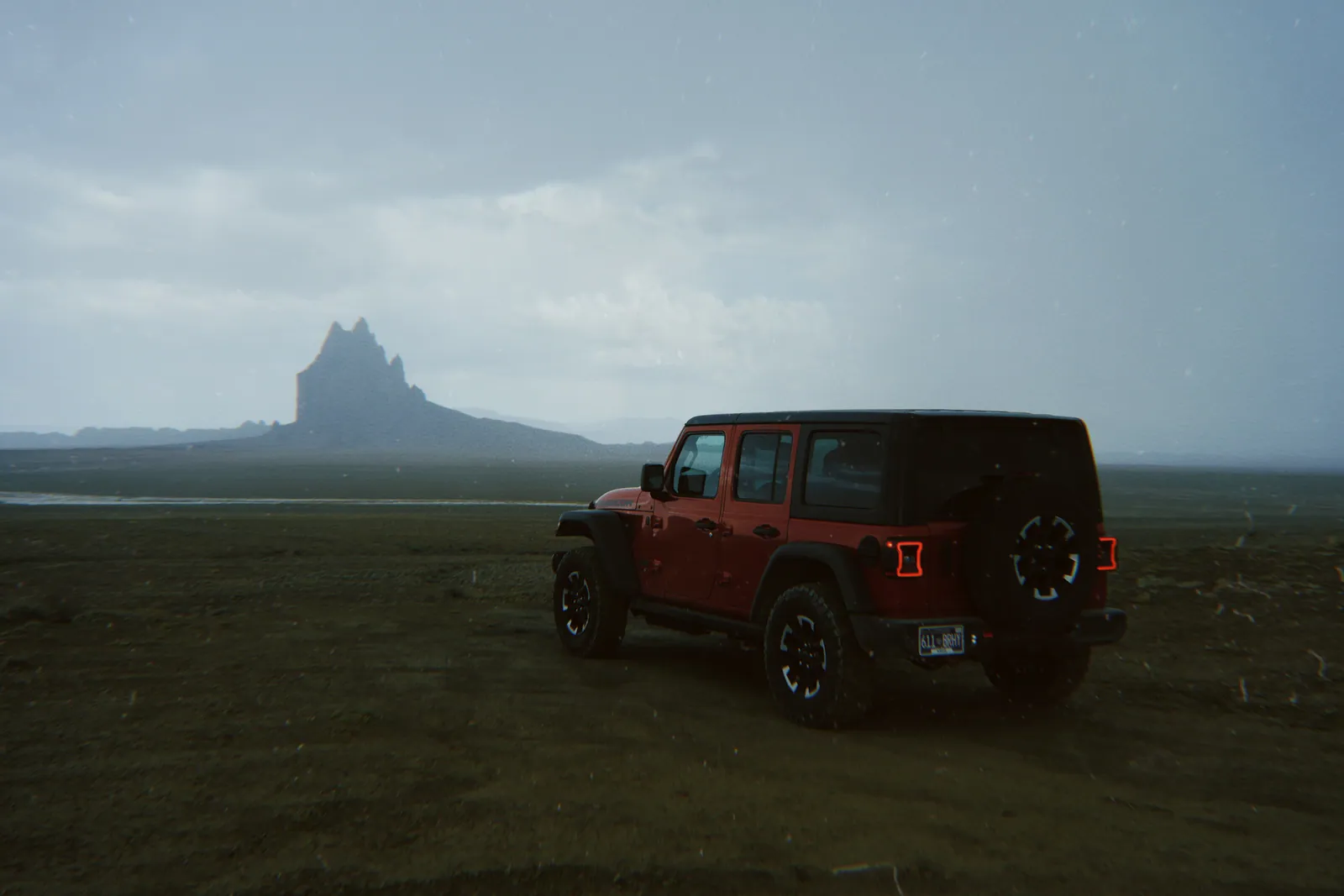 A Jeep parked beneath a desert peak at dusk